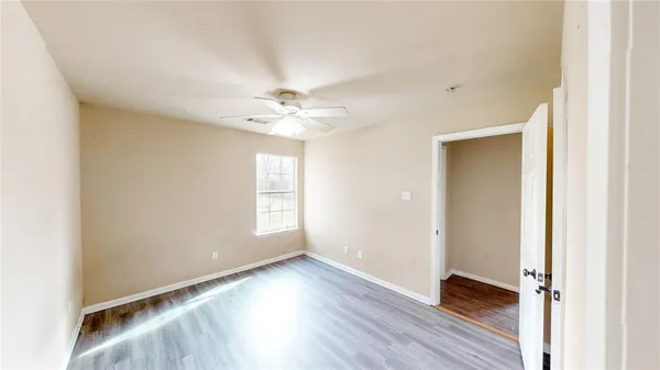 a view of an empty room with wooden floor and a window