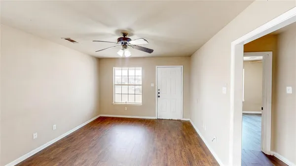 a view of an empty room with a window and wooden floor