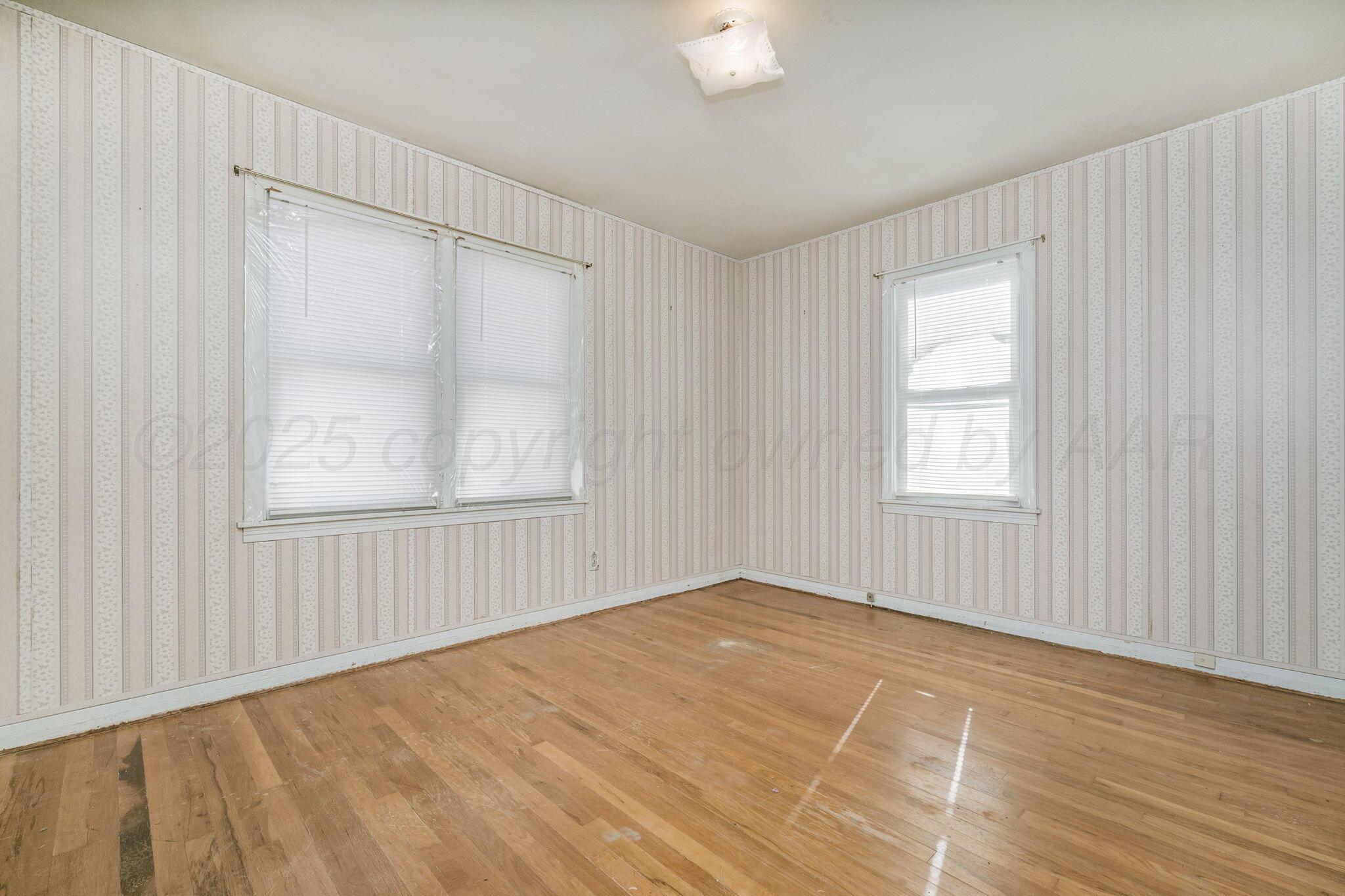 2133 Hamilton Street Pampa, TX 79065 - Photo 16 of 21 a view of an empty room with wooden floor and a window