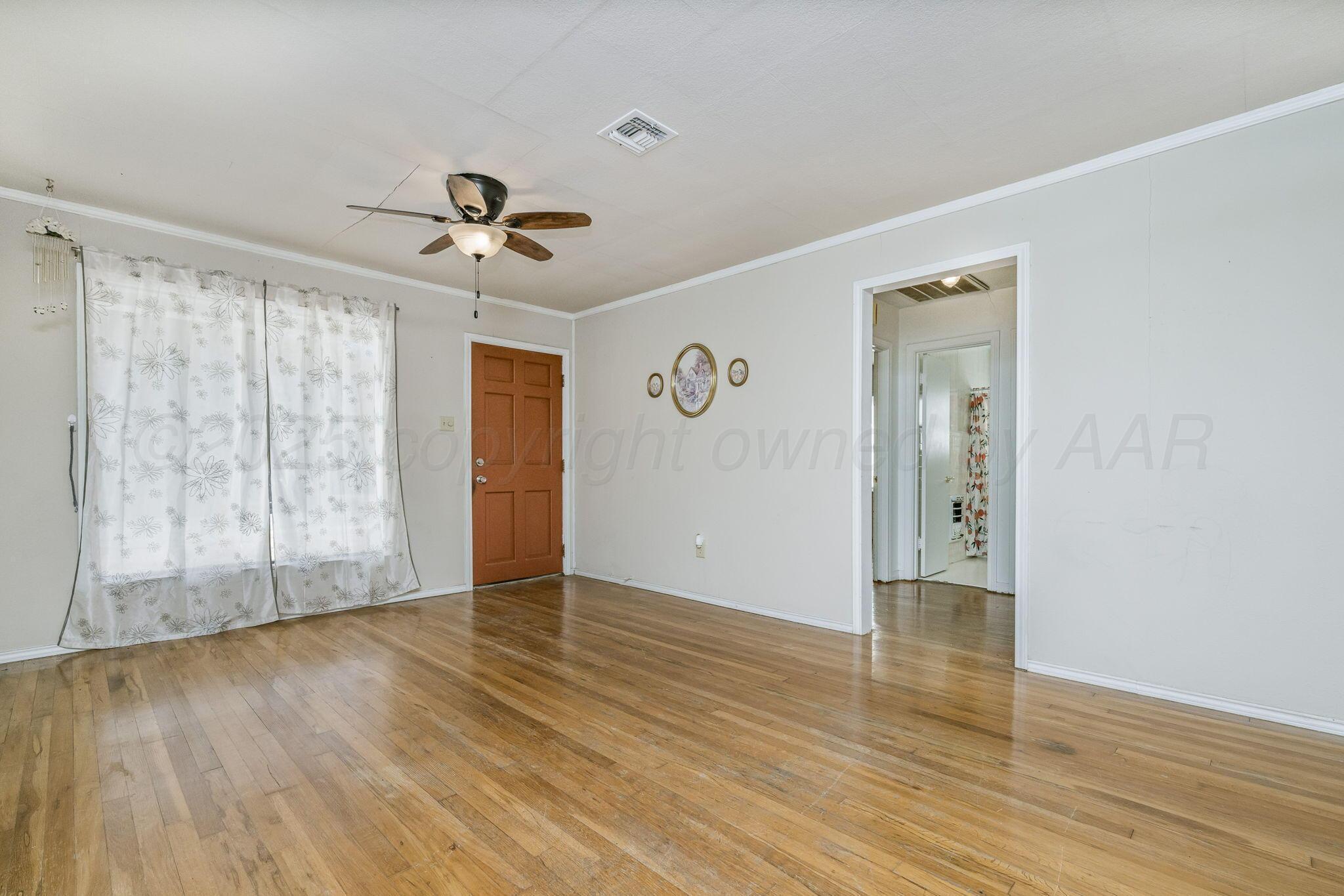 2133 Hamilton Street Pampa, TX 79065 - Photo 4 of 21 wooden floor in an empty room with a window
