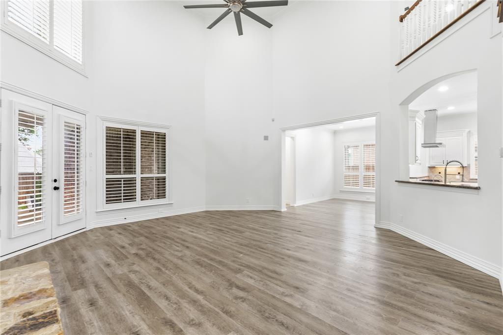 967 East Bethel School Road Coppell, TX 75019 - Photo 17 of 39 Spacious living area featuring high ceilings, wood-finish flooring, a stone fireplace, and plantation-shutter windows