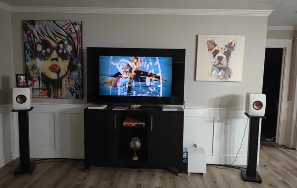 a living room with stainless steel appliances kitchen island granite countertop a stove a sink a refrigerator white cabinets and wooden floor