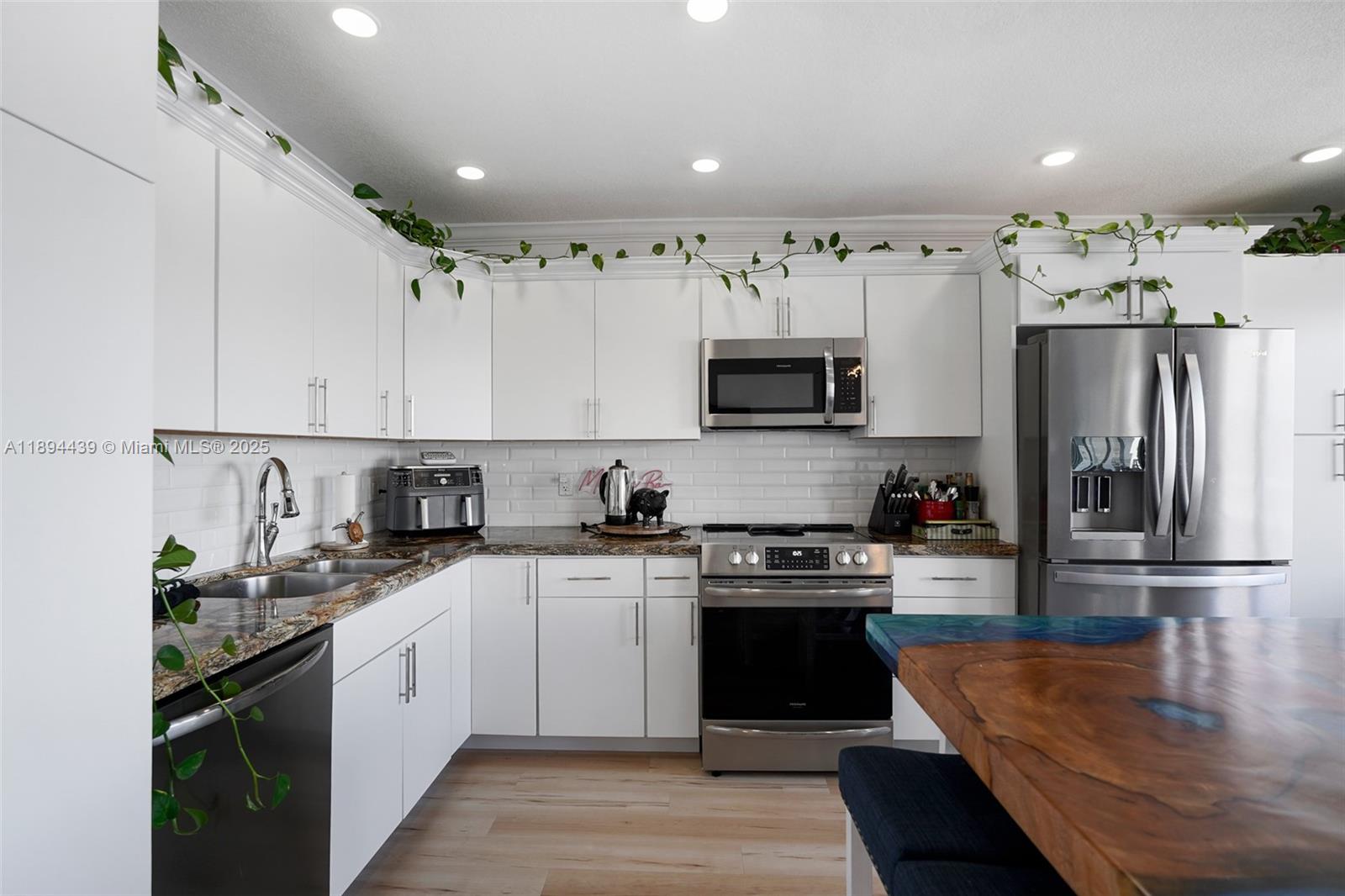 1201 South Riverside Drive, Unit 301 Pompano Beach, FL 33062 - Photo 7 of 24 a kitchen with stainless steel appliances granite countertop a refrigerator a sink dishwasher a stove and white cabinets with wooden floor
