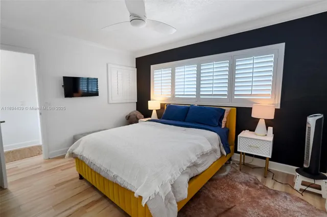 a bedroom with a bed a flat screen tv and a large window