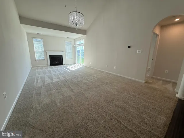 an empty room with a fireplace and chandelier