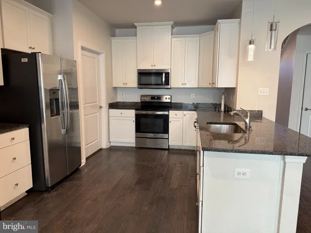 a kitchen with granite countertop a refrigerator stove and sink