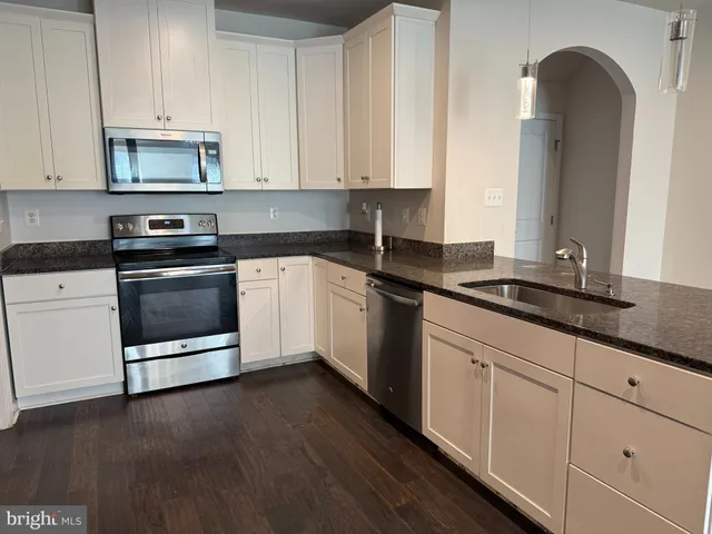 a kitchen with granite countertop white cabinets and appliances