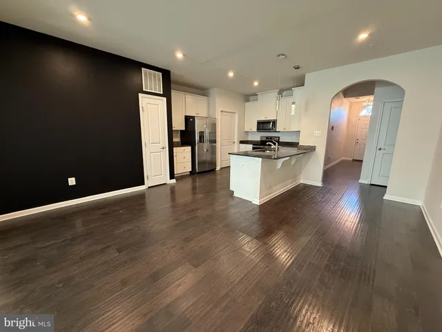 a open kitchen with stainless steel appliances granite countertop a refrigerator a sink dishwasher a stove and a dining table with wooden floor