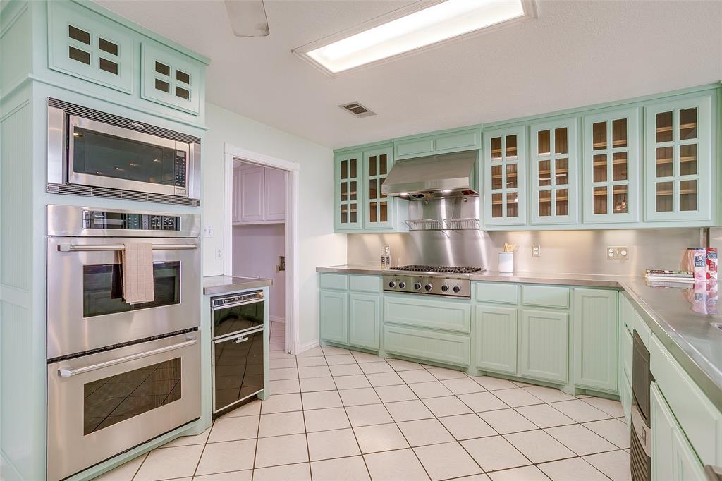 11484 Moran Road Azle, TX 76020 - Photo 11 of 40 Kitchen with stainless steel counters, appliances with stainless steel finishes, glass insert cabinets, under cabinet range hood, and light tile patterned floors