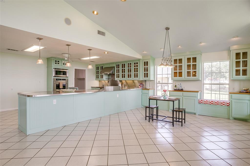 11484 Moran Road Azle, TX 76020 - Photo 12 of 40 Kitchen with green cabinets, glass insert cabinets, a peninsula, pendant lighting, and vaulted ceiling