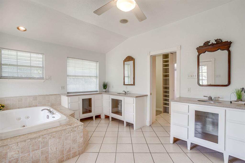 11484 Moran Road Azle, TX 76020 - Photo 21 of 40 Full bath with a walk in closet, two vanities, vaulted ceiling, a whirlpool tub, and light tile patterned floors