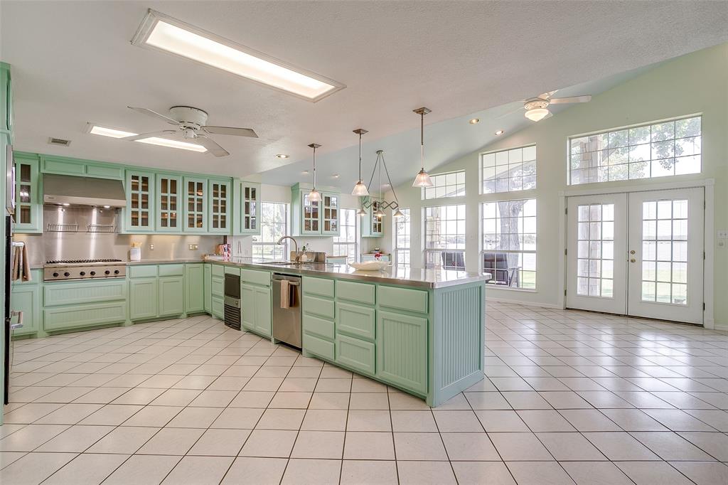 11484 Moran Road Azle, TX 76020 - Photo 10 of 40 Kitchen with a ceiling fan, glass insert cabinets, pendant lighting, light tile patterned flooring, and high vaulted ceiling