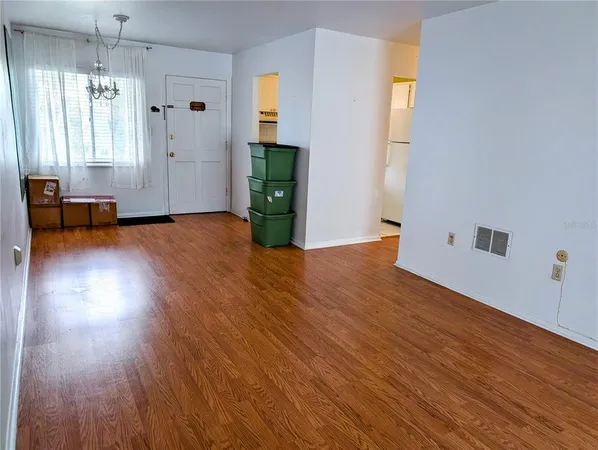 a view of empty room with wooden floor and fan