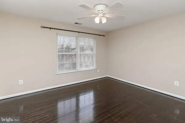an empty room with wooden floor and ceiling fan