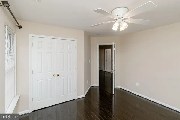 an empty room with wooden floor ceiling fan and windows