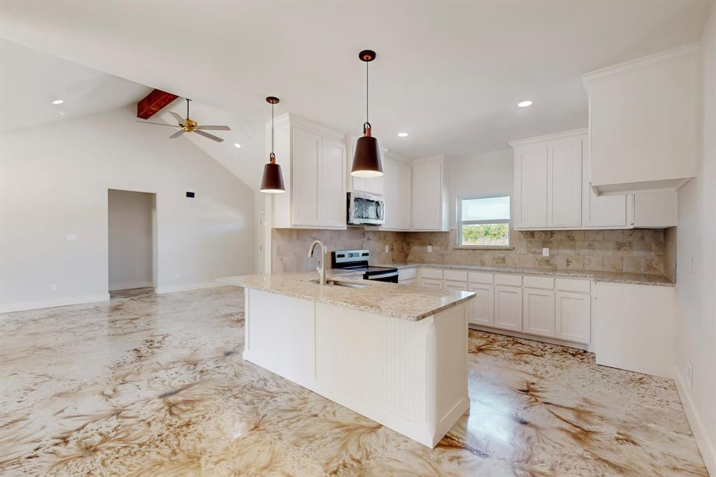 2030 Shoemaker Road Bellevue, TX 76228 - Photo 2 of 6 a kitchen with kitchen island sink stove and white cabinets