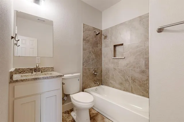 a bathroom with a granite countertop toilet a sink and a bathtub