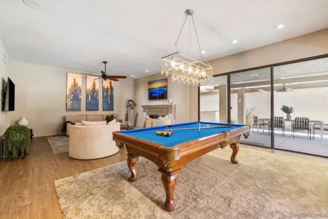 a dining room with wooden floor a chandelier a wooden table and chairs