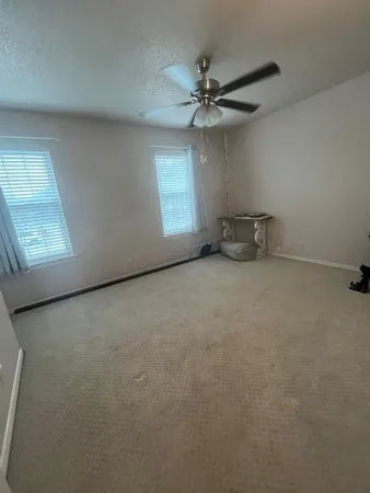 an empty room with windows and fan