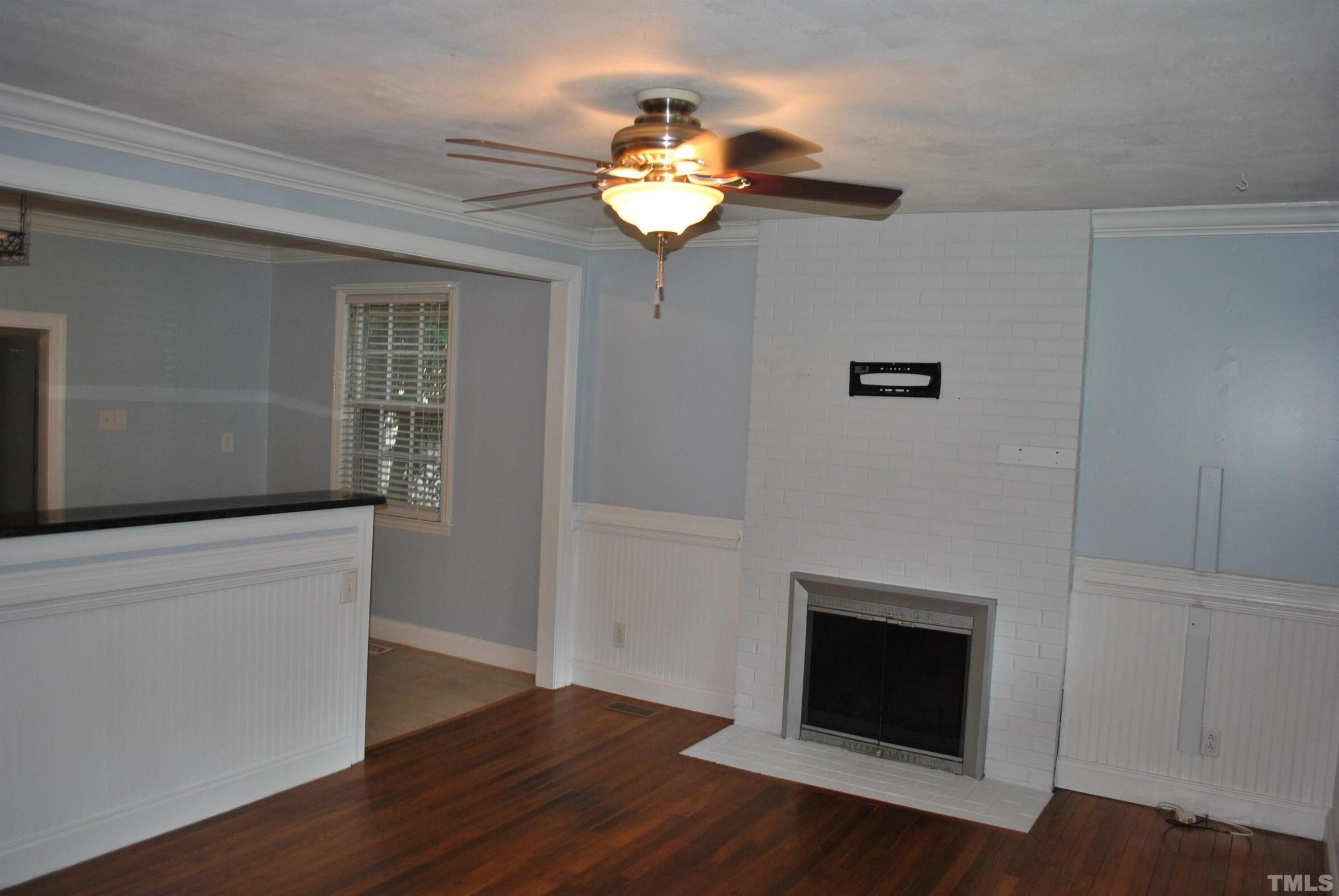2106 Brewer Street Raleigh, NC 27608 - Photo 10 of 38 a view of a livingroom with a fireplace wooden floor and a window