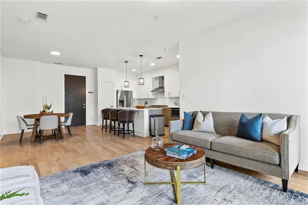 a living room with furniture and a dining table with wooden floor
