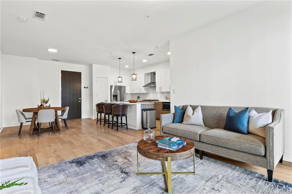 775 Juniper Street Northeast, Unit 613 Atlanta, GA 30308 - Photo 10 of 39 a living room with furniture and a dining table with wooden floor