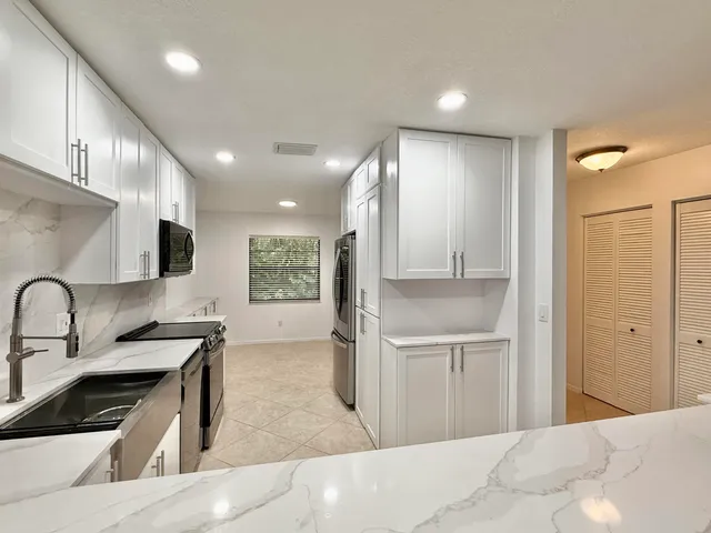 a kitchen with stainless steel appliances granite countertop a sink and a refrigerator