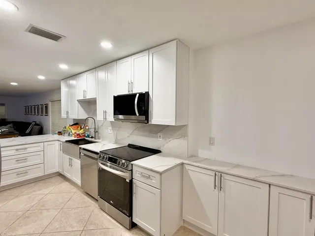 a kitchen with granite countertop white cabinets and stainless steel appliances