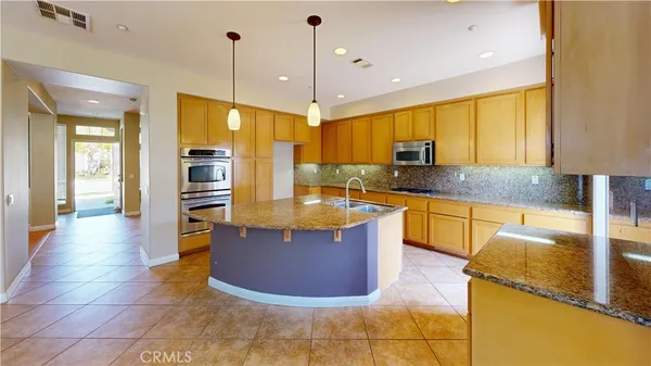 a kitchen with stainless steel appliances granite countertop a sink a stove and a wooden floors