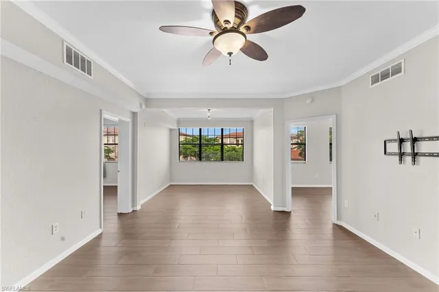 a view of an empty room with window and wooden floor