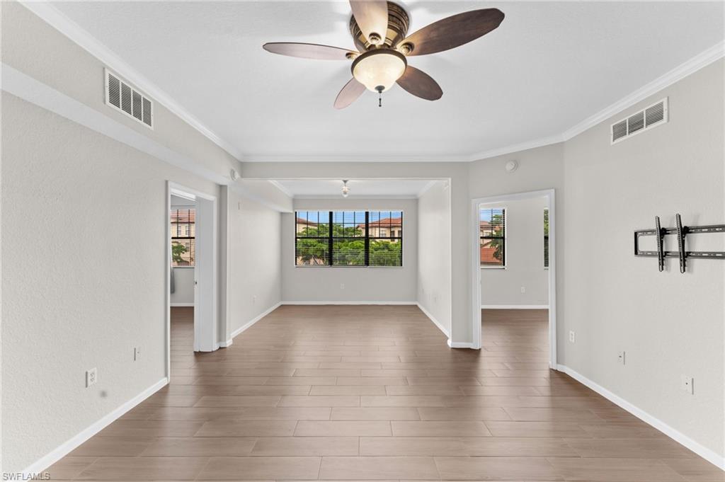 12920 Positano Circle, Unit 303 Naples, FL 34105 - Photo 3 of 21 a view of an empty room with window and wooden floor