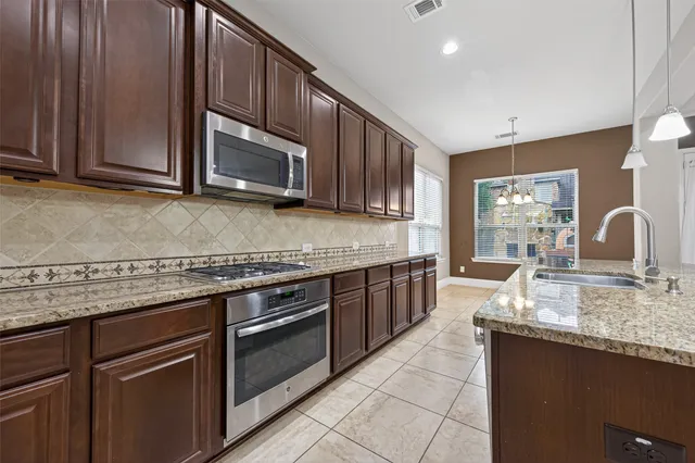 a kitchen with kitchen island granite countertop a stove a sink and a microwave
