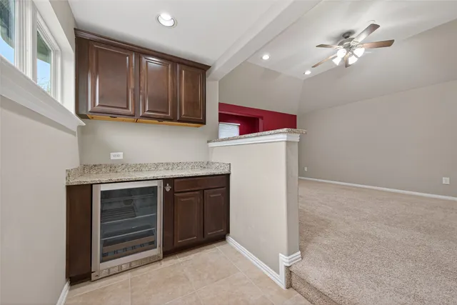 an empty room with chandelier fan and windows