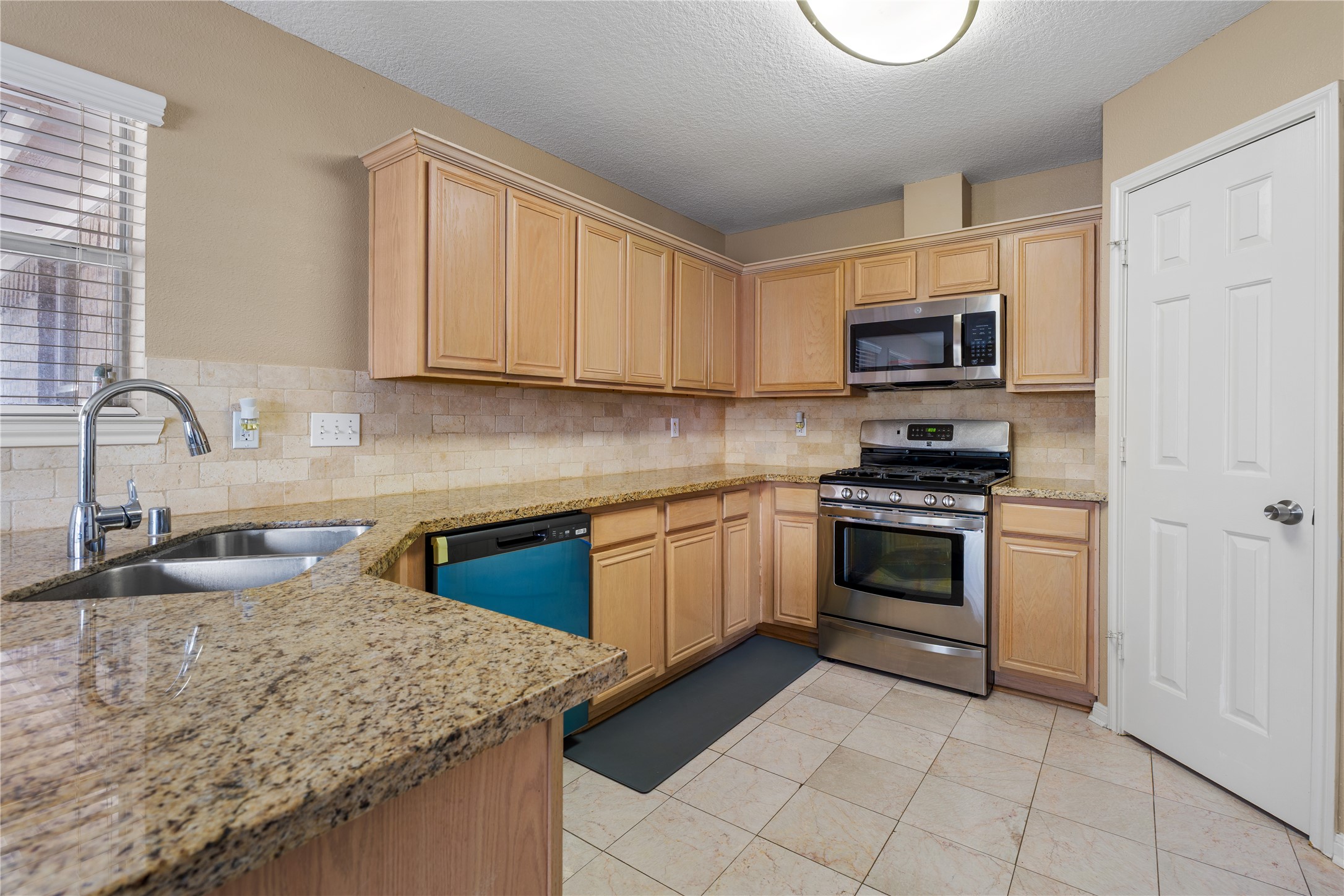 21074 Southern Colony Court Katy, TX 77449 - Photo 11 of 27 a kitchen with granite countertop a sink a stove top oven and cabinetry