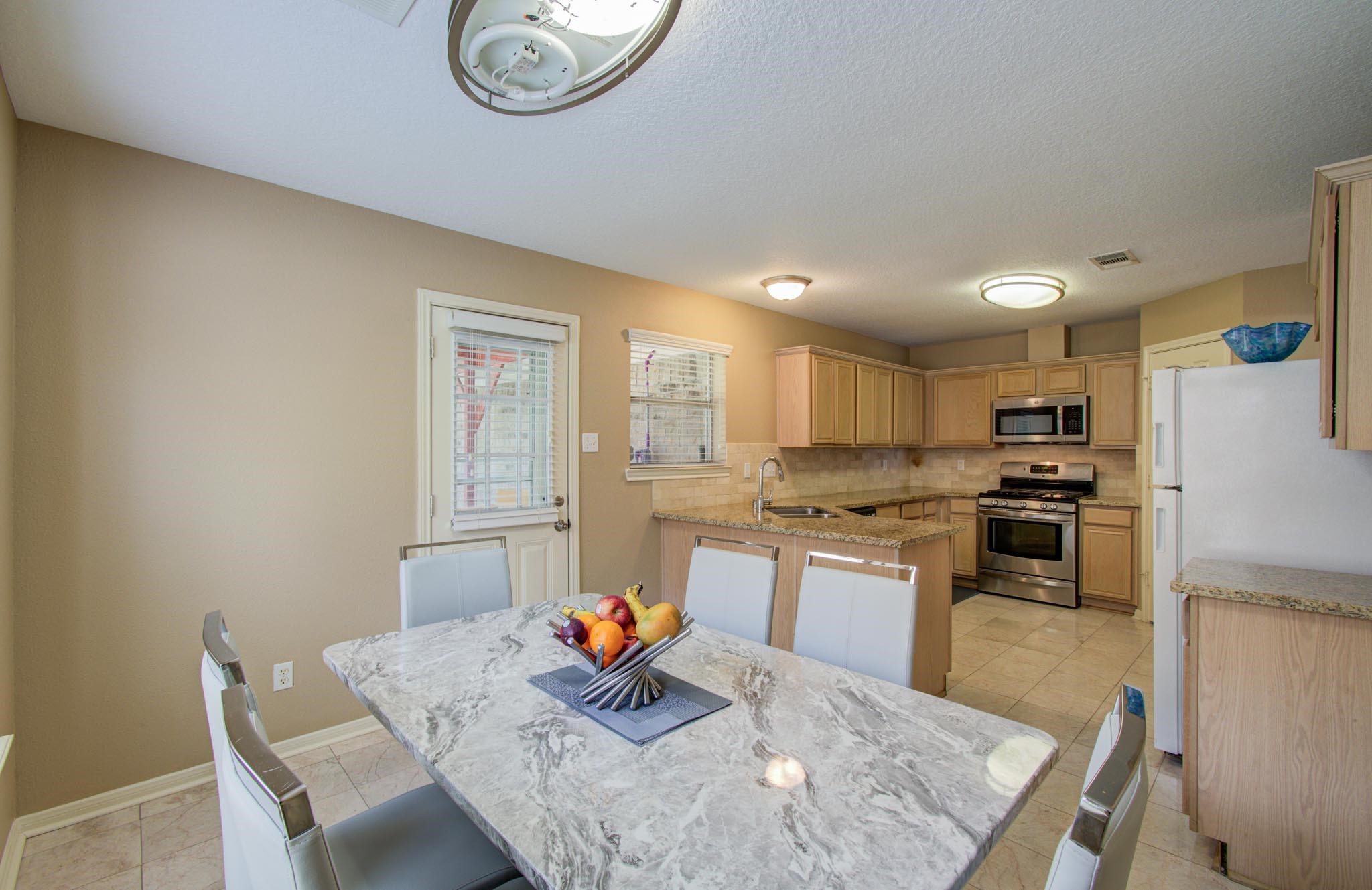 21074 Southern Colony Court Katy, TX 77449 - Photo 13 of 27 a kitchen with stainless steel appliances granite countertop a stove top oven a sink a dining table and chairs with wooden floor