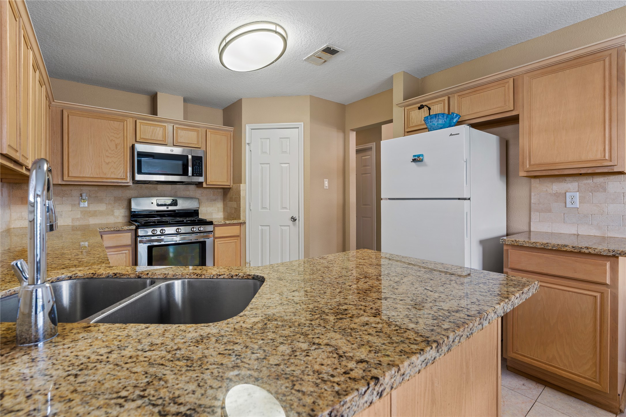21074 Southern Colony Court Katy, TX 77449 - Photo 4 of 27 a kitchen with kitchen island a stove a sink and a refrigerator
