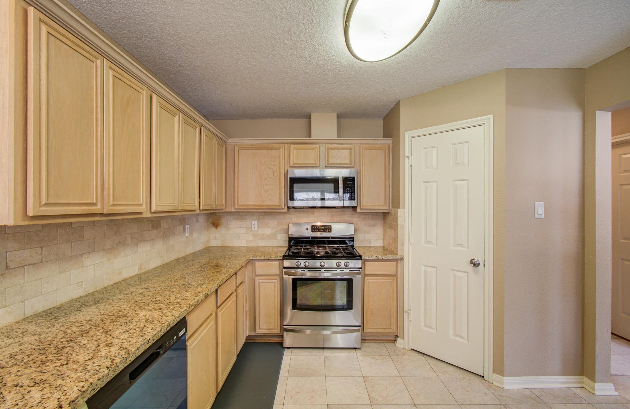 21074 Southern Colony Court Katy, TX 77449 - Photo 10 of 27 a kitchen with granite countertop white cabinets and stainless steel appliances