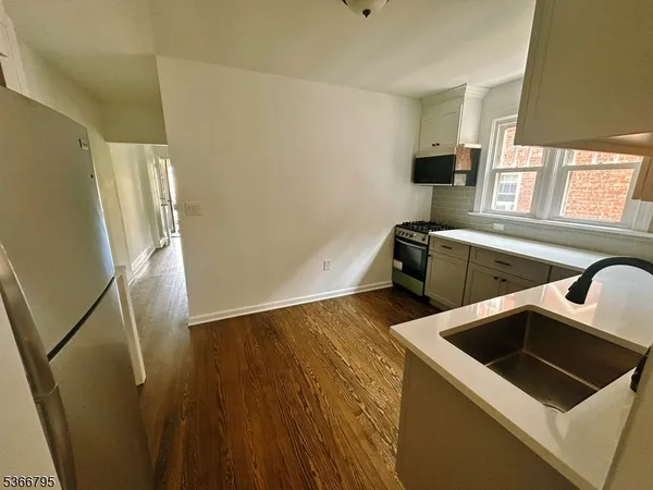 a view of a kitchen with wooden floor and electronic appliances