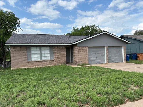 a brick house next to a yard with large trees