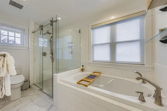 a bathroom with a tub a toilet and a shower