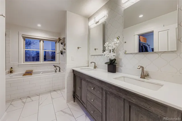 a spacious bathroom with a double vanity sink mirror and bathtub