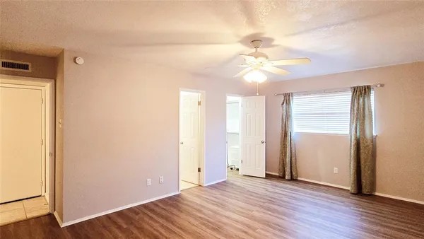 an empty room with wooden floor and a ceiling fan