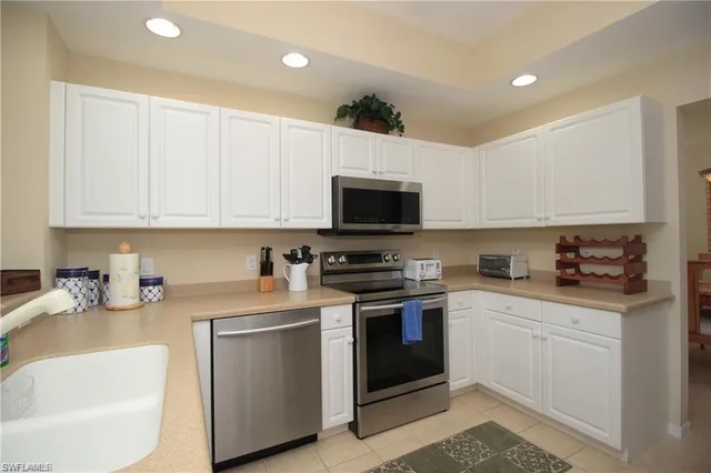 a kitchen with stainless steel appliances kitchen island granite countertop a refrigerator a sink a stove a dining table and chairs with wooden floor