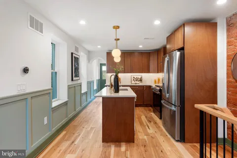 a kitchen with stainless steel appliances granite countertop a refrigerator and a wooden floor
