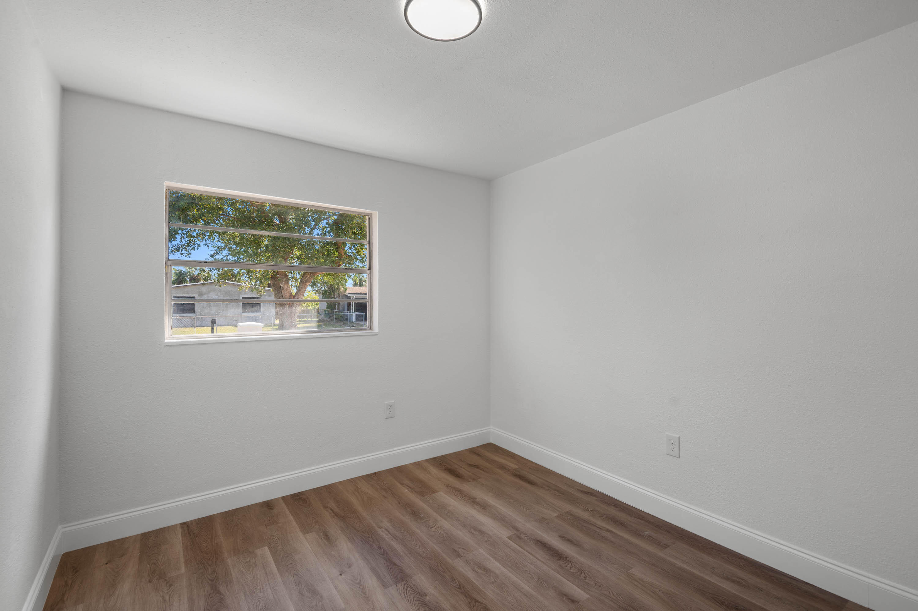 515 A Lane Cocoa, FL 32926 - Photo 16 of 31 a view of an empty room with wooden floor and a window