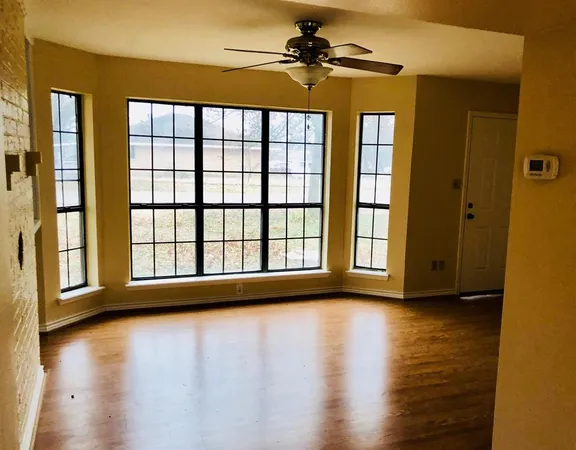 a view of empty room with wooden floor and fan
