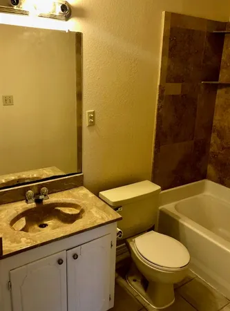 a bathroom with a granite countertop toilet and a sink