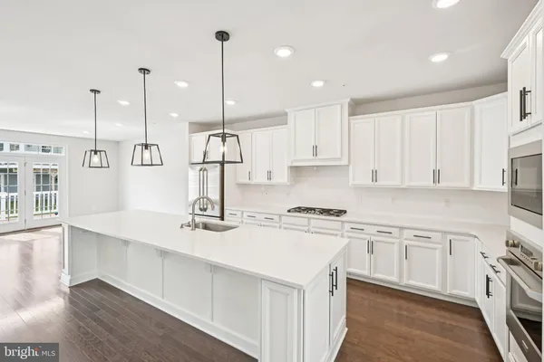 a kitchen with stainless steel appliances granite countertop a sink a stove a refrigerator and white cabinets with wooden floor