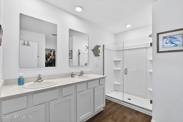 a spacious bathroom with double sink shower and two mirror
