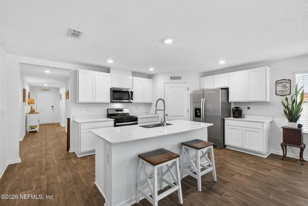 a kitchen with refrigerator a microwave and chairs